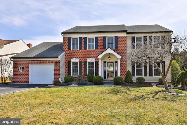 colonial-style house with brick siding, a shingled roof, a front lawn, driveway, and an attached garage