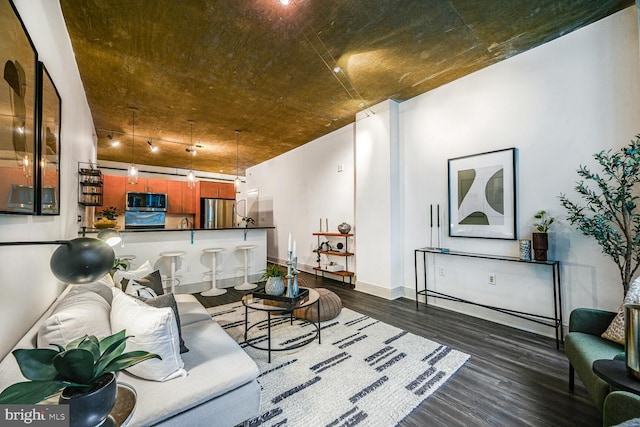 living area with dark wood-style floors, baseboards, and track lighting