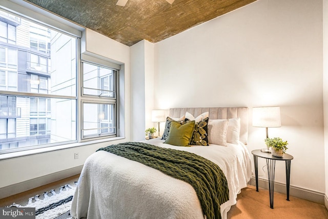 carpeted bedroom featuring multiple windows and baseboards