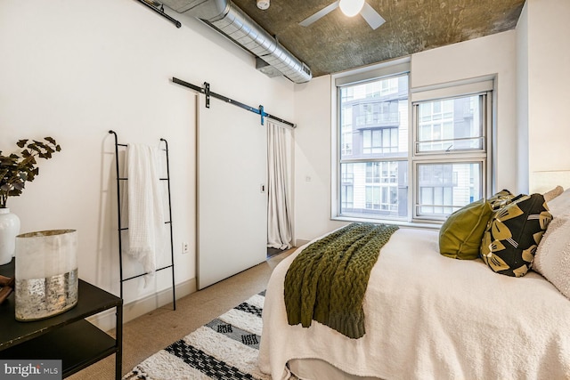 carpeted bedroom featuring a barn door and a ceiling fan