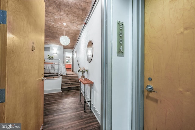 corridor with dark wood-style floors, stairs, and baseboards