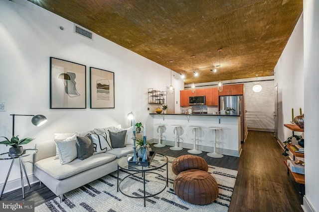 living room featuring dark wood-style flooring, visible vents, and baseboards