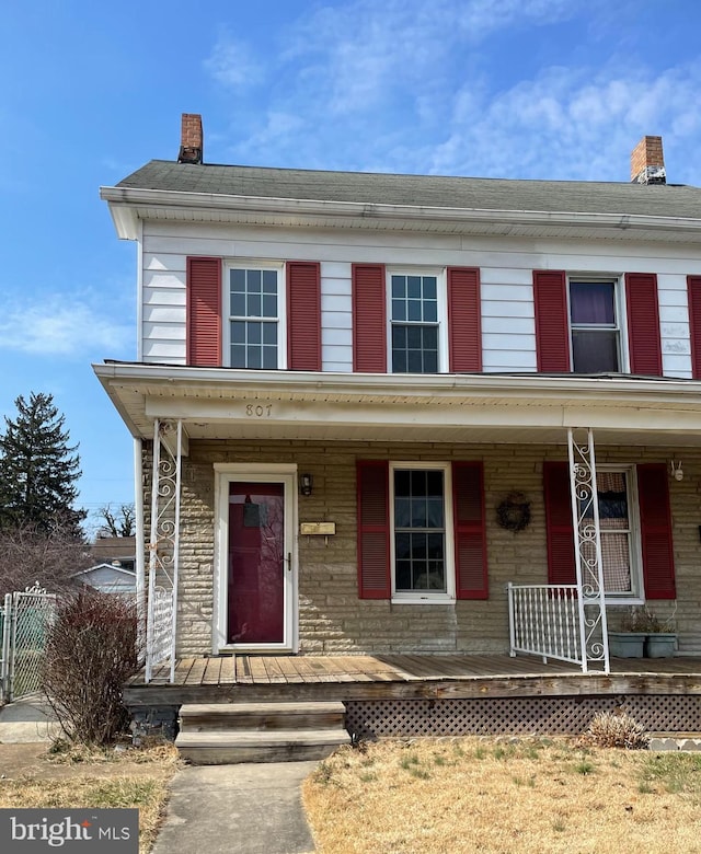 view of front of home featuring covered porch and a chimney