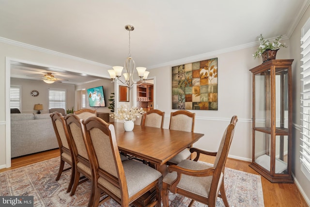 dining room with light wood-type flooring, baseboards, ornamental molding, and ceiling fan with notable chandelier