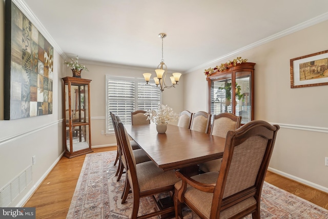 dining space featuring crown molding, a notable chandelier, and light wood-style floors