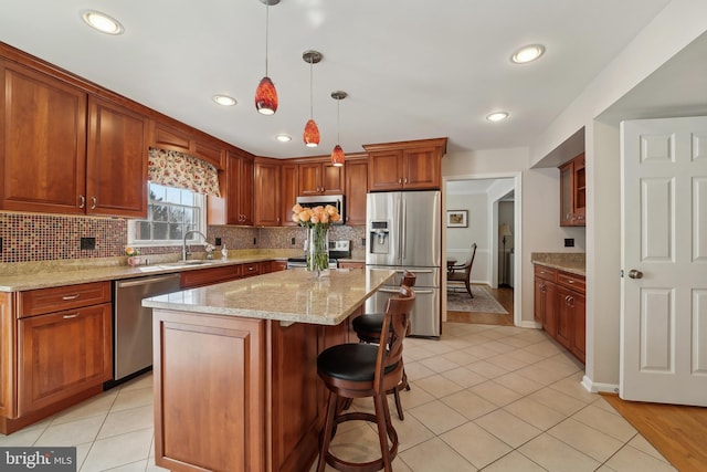 kitchen with backsplash, pendant lighting, light stone counters, light tile patterned flooring, and stainless steel appliances