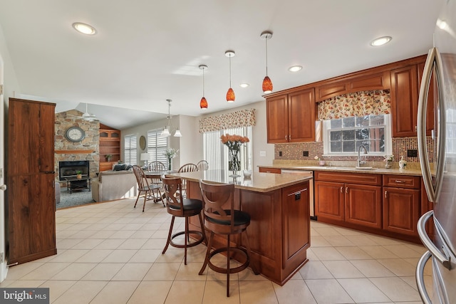 kitchen with open floor plan, vaulted ceiling, light tile patterned floors, stainless steel appliances, and a sink