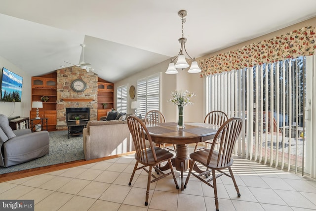 dining space with light tile patterned floors, built in features, a fireplace, and lofted ceiling