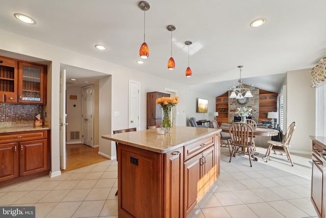 kitchen featuring light stone counters, light tile patterned floors, visible vents, hanging light fixtures, and decorative backsplash