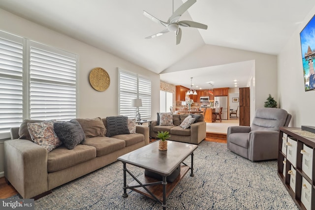 living room featuring light wood finished floors, a ceiling fan, and vaulted ceiling