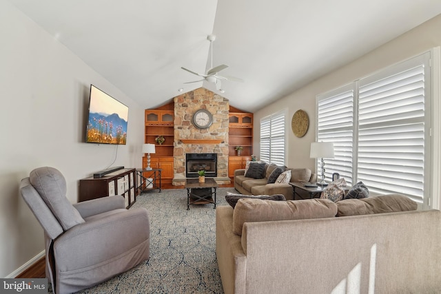 living area featuring built in shelves, a ceiling fan, baseboards, a fireplace, and vaulted ceiling