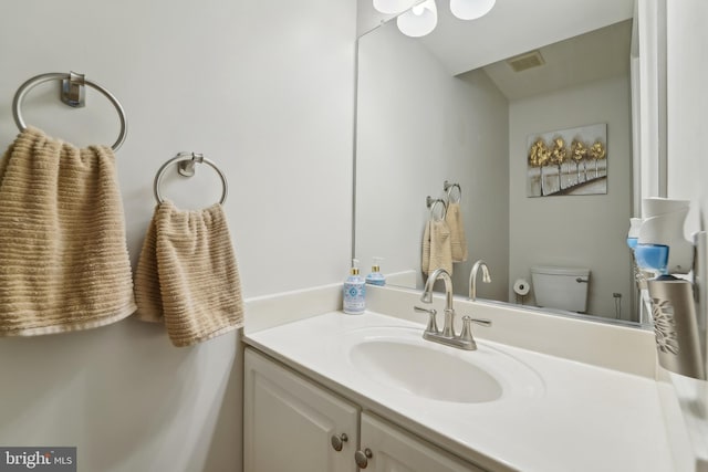 half bathroom featuring visible vents, toilet, and vanity