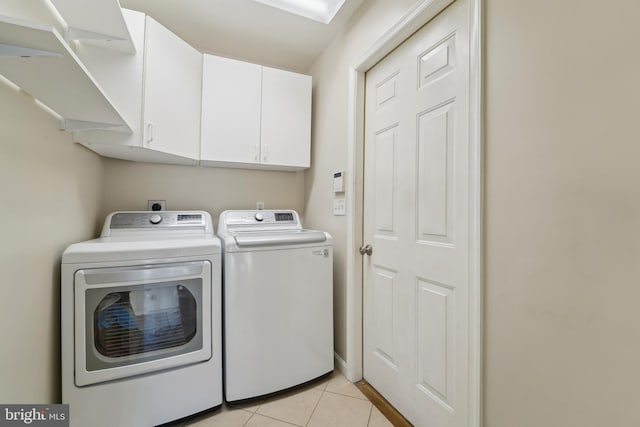 washroom with washer and dryer, light tile patterned floors, and cabinet space