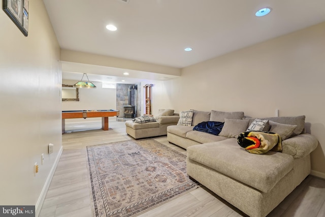 living room featuring recessed lighting, light wood-type flooring, baseboards, and a wood stove