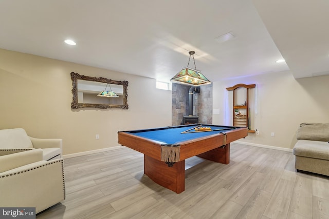 recreation room with light wood finished floors, pool table, baseboards, recessed lighting, and a wood stove