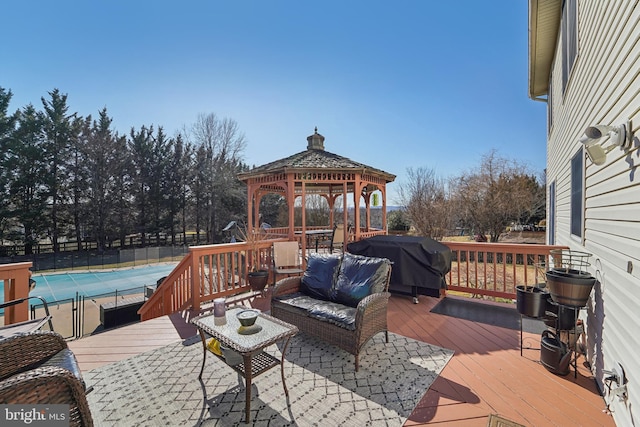 wooden deck featuring a gazebo, an outdoor hangout area, a grill, and fence