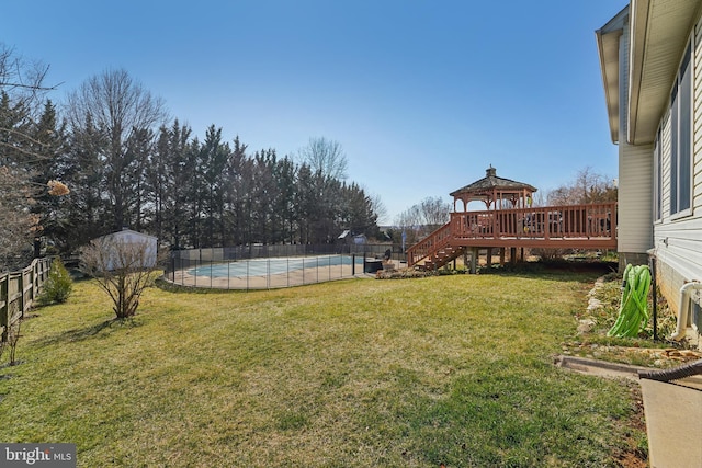 view of yard with a gazebo, a fenced in pool, a wooden deck, and a fenced backyard