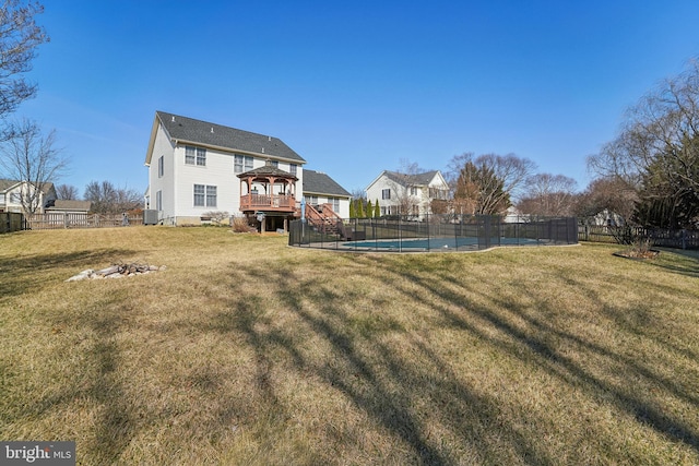 view of yard with fence, a fenced in pool, an outdoor fire pit, a wooden deck, and central AC