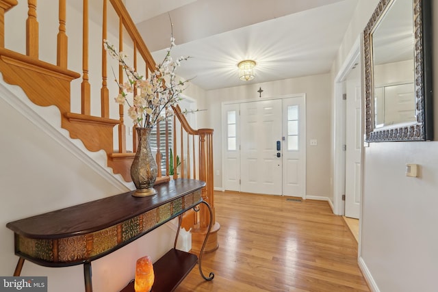 foyer with stairway, light wood-type flooring, and baseboards