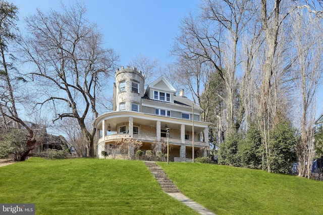 view of front of home featuring a ceiling fan, a balcony, and a front lawn