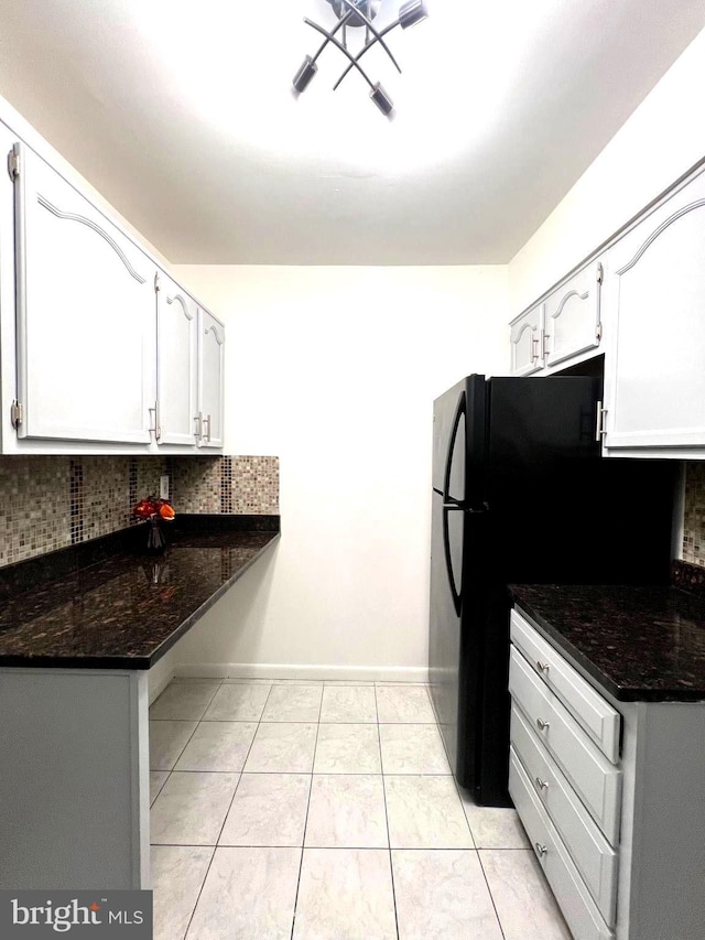 kitchen with light tile patterned floors, tasteful backsplash, white cabinets, and dark stone countertops