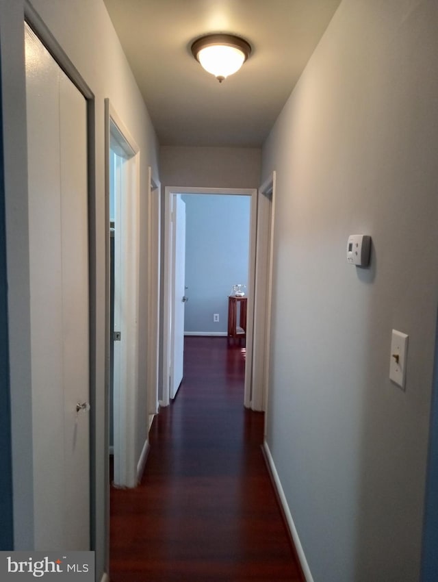 hall featuring dark wood-style floors and baseboards