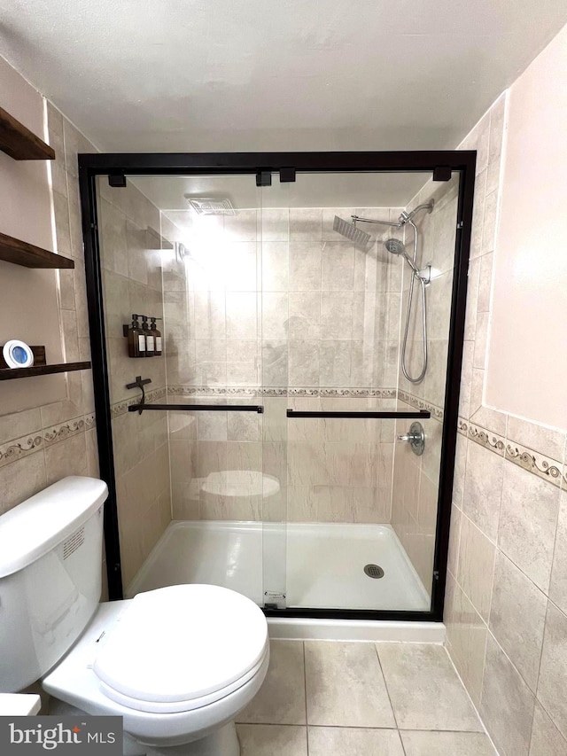 bathroom with toilet, a stall shower, and tile walls