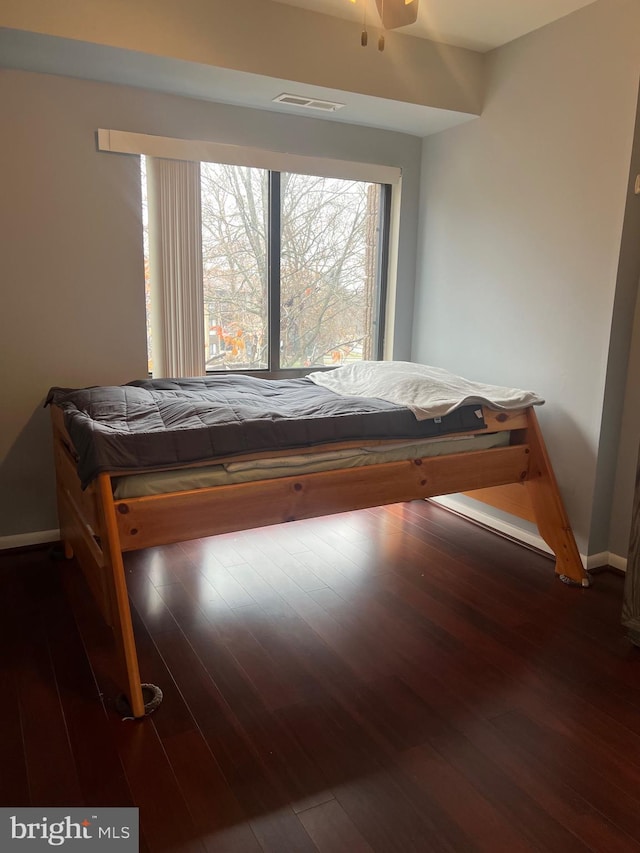 bedroom with wood finished floors, visible vents, and baseboards