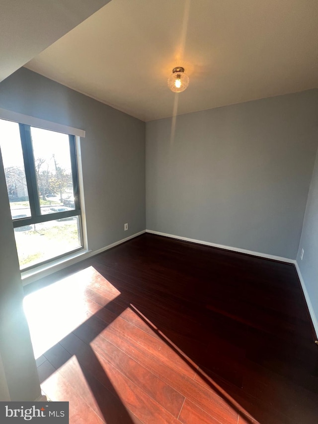 spare room with baseboards and wood finished floors