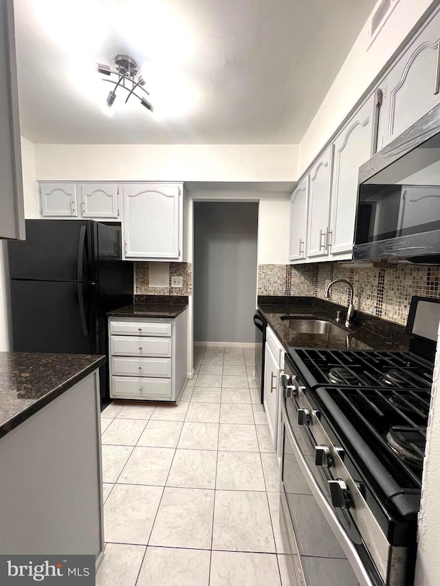 kitchen featuring light tile patterned floors, stainless steel appliances, decorative backsplash, a sink, and baseboards