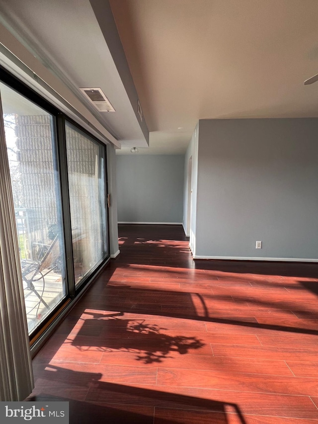 hall featuring baseboards, visible vents, and wood finished floors