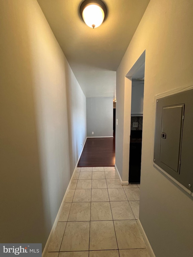 hallway with light tile patterned floors, electric panel, and baseboards