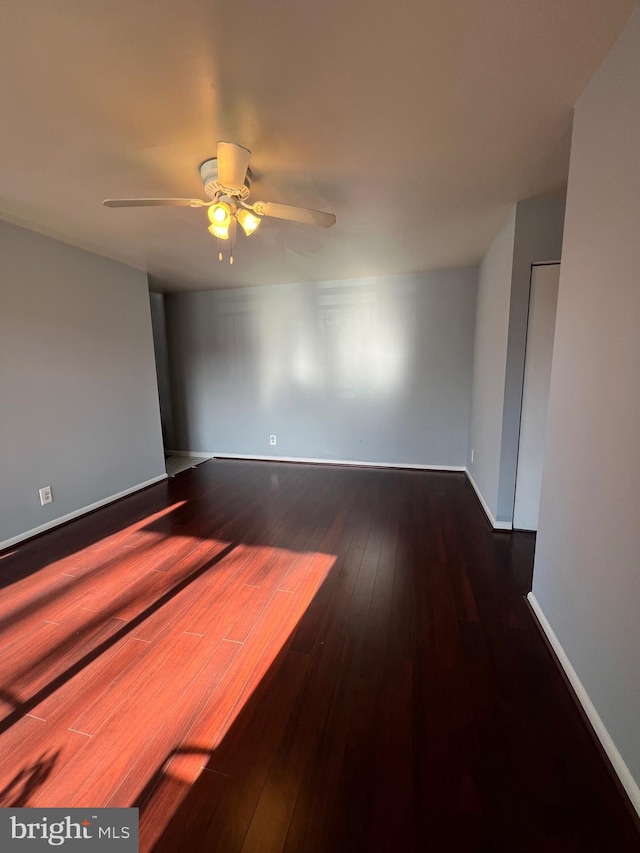 empty room with hardwood / wood-style floors, a ceiling fan, and baseboards