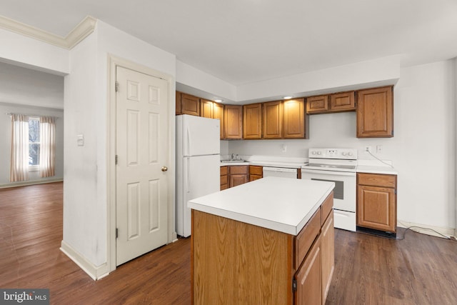 kitchen featuring brown cabinets, dark wood finished floors, light countertops, a sink, and white appliances