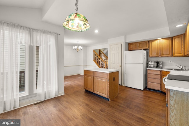 kitchen featuring dark wood-style floors, a center island, freestanding refrigerator, light countertops, and a sink