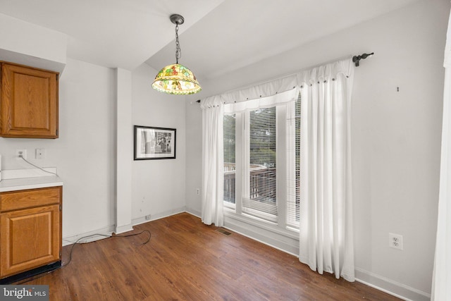 unfurnished dining area with dark wood-style floors, visible vents, and baseboards