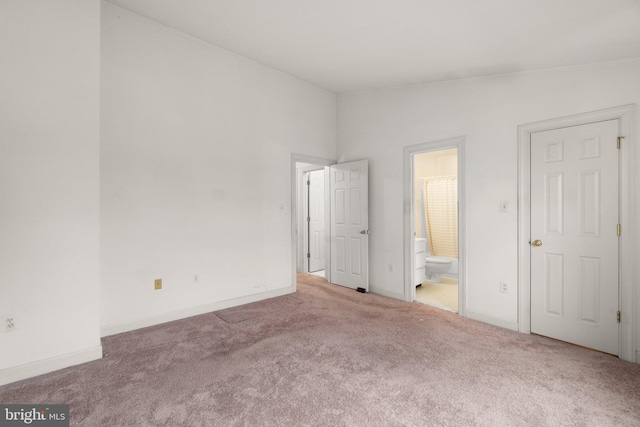 unfurnished bedroom featuring baseboards, vaulted ceiling, carpet flooring, and ensuite bathroom