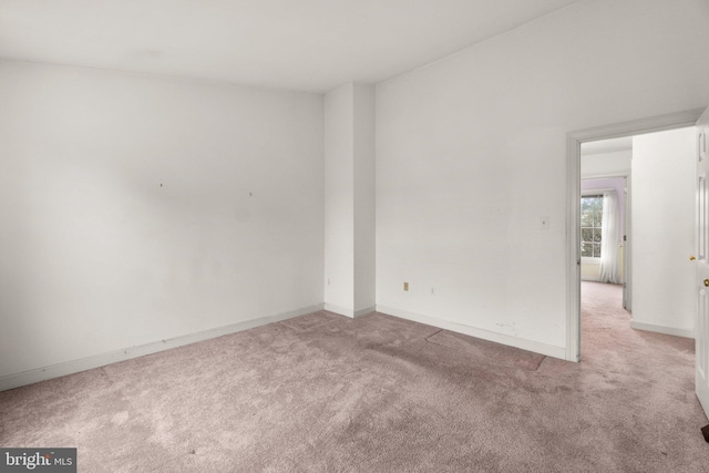 unfurnished room featuring light colored carpet and baseboards