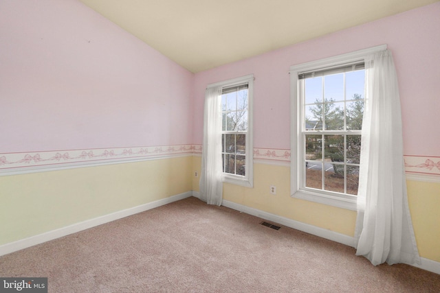 carpeted spare room with lofted ceiling, baseboards, and visible vents