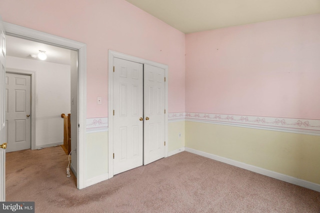 unfurnished bedroom featuring a closet, light carpet, and baseboards