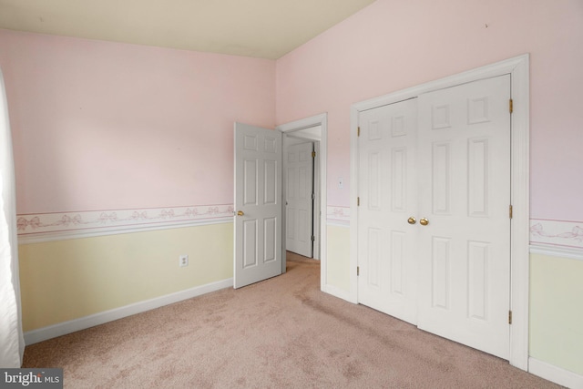 unfurnished bedroom featuring carpet, a closet, and baseboards