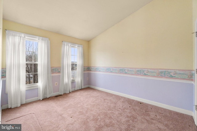 carpeted empty room with visible vents, vaulted ceiling, and baseboards