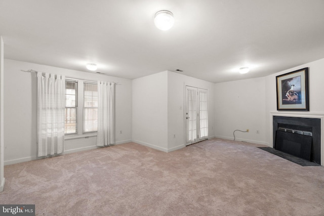 unfurnished living room with a fireplace with flush hearth, baseboards, and carpet flooring