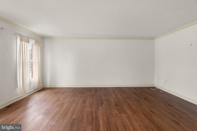 spare room featuring ornamental molding, visible vents, baseboards, and wood finished floors