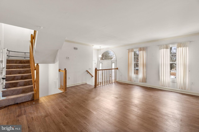 unfurnished living room featuring ornamental molding and wood finished floors