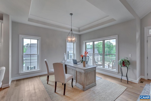 office space featuring a chandelier, a tray ceiling, light wood-style flooring, and baseboards