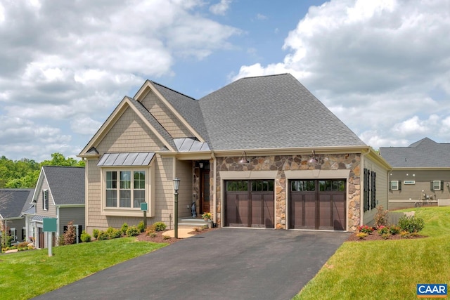 craftsman-style house featuring an attached garage, a standing seam roof, stone siding, driveway, and a front lawn