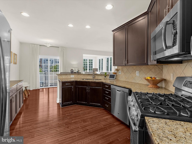 8512 Pine Springs Dr, Severn, MD 21144 - kitchen with appliances with stainless steel finishes, decorative backsplash, dark brown cabinets, dark wood-style flooring, and a peninsula