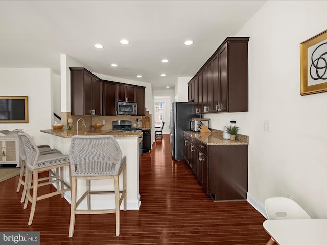 8512 Pine Springs Dr, Severn, MD 21144 - kitchen featuring appliances with stainless steel finishes, dark brown cabinetry, dark wood-type flooring, light stone counters, and recessed lighting