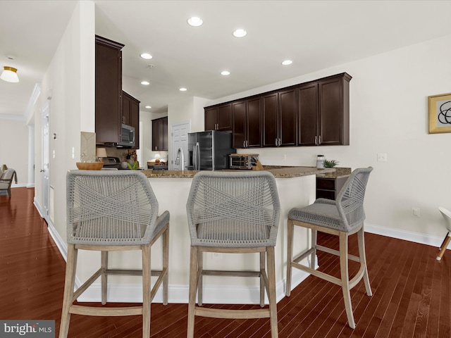 8512 Pine Springs Dr, Severn, MD 21144 - kitchen featuring appliances with stainless steel finishes, dark brown cabinetry, dark wood-style flooring, light stone counters, and baseboards